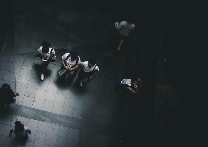 学生坐在校园草地上放松休息，阳光明媚，表情平静，身旁放着书包，体现心理健康的重要性